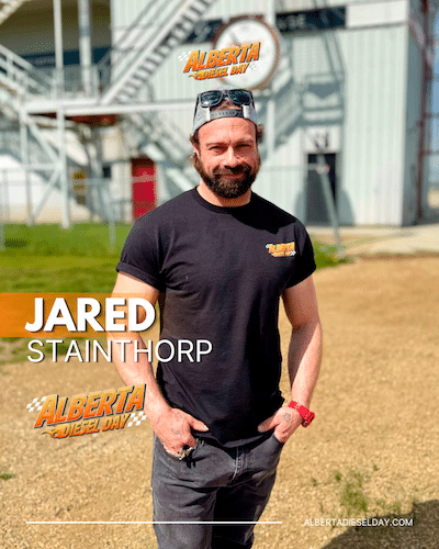 Portrait of Jared Stainthorpe outdoors in a black T-shirt with Alberta Diesel Day logos and his name overlaid on the image, on a dirt field.